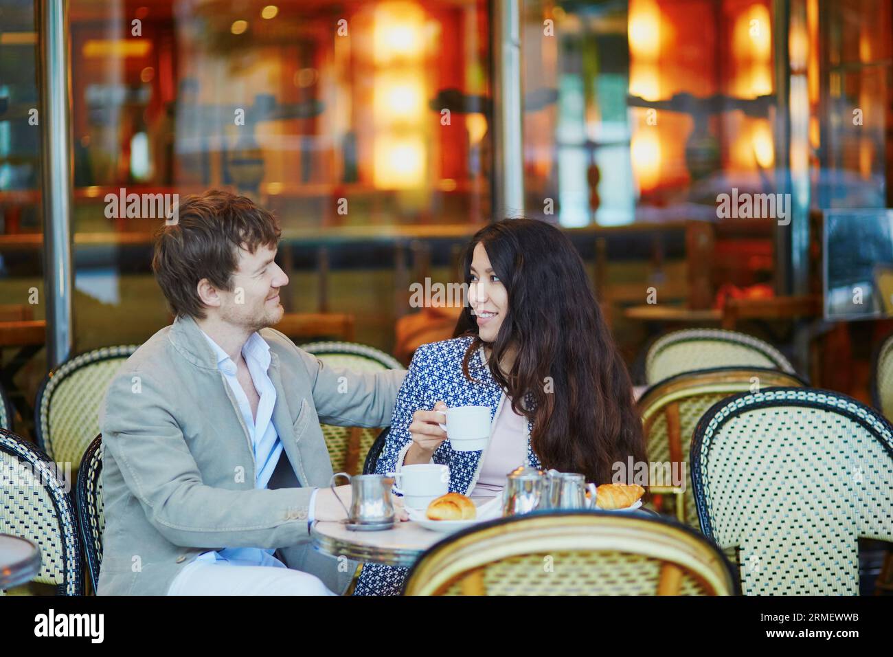 Romantica coppia che beve caffè e mangia tradizionali croissant francesi nel caffè di Parigi Foto Stock