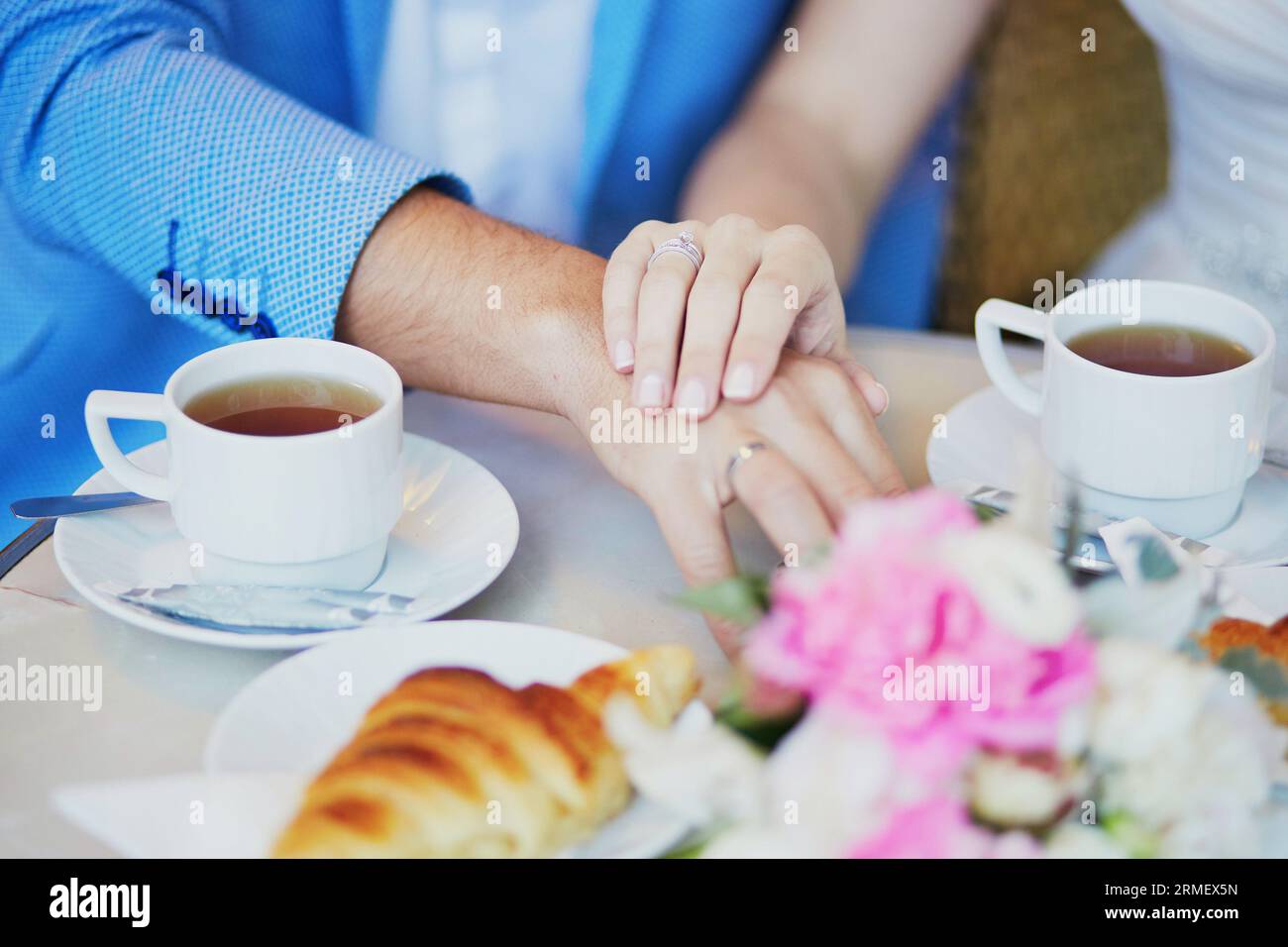 Solo una coppia sposata che si tiene per mano nel bar parigino il giorno del loro matrimonio Foto Stock
