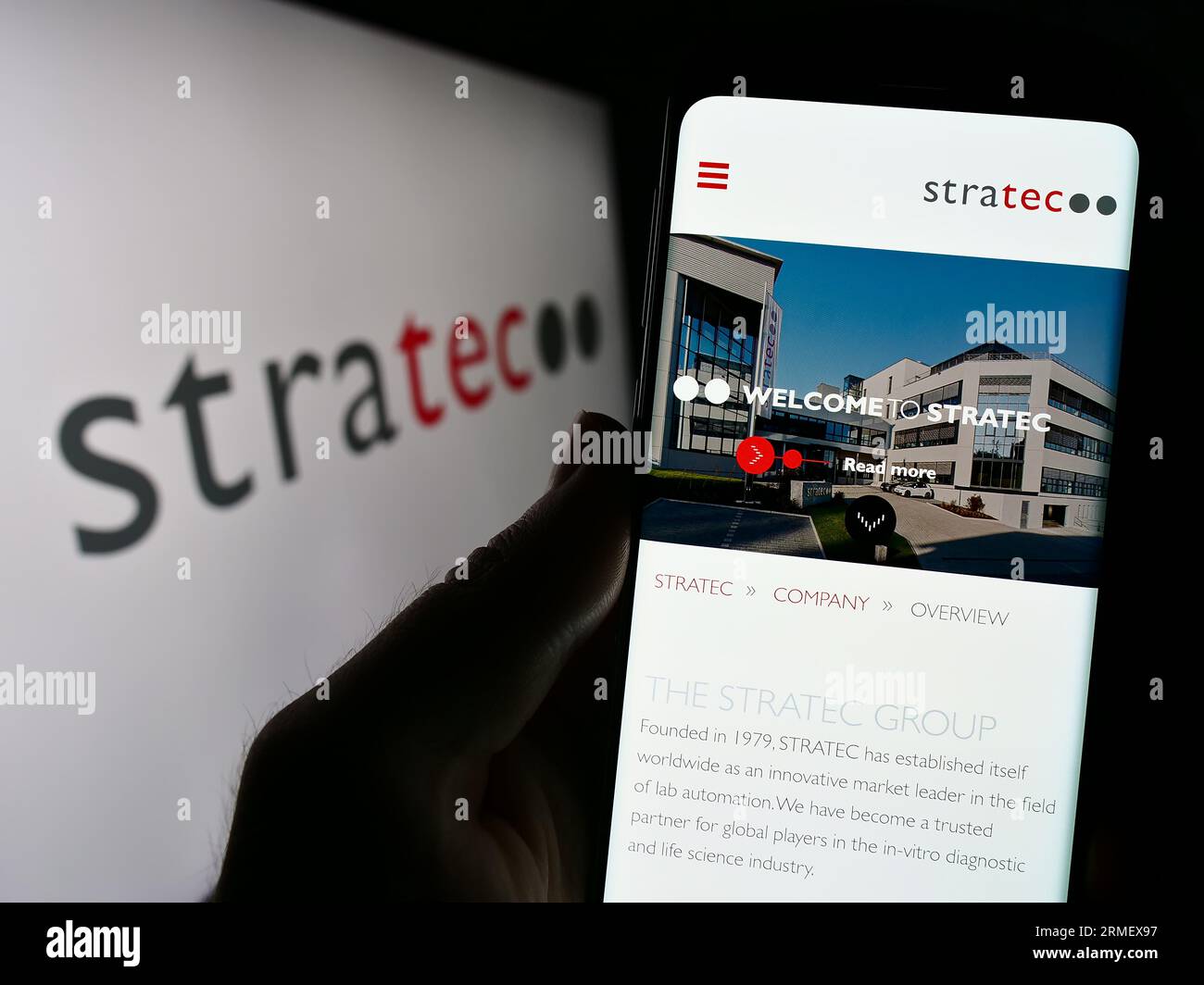 Persona che tiene il cellulare con il sito Web della società tedesca di diagnostica STRATEC se sullo schermo davanti al logo. Concentrarsi sul centro del display del telefono. Foto Stock