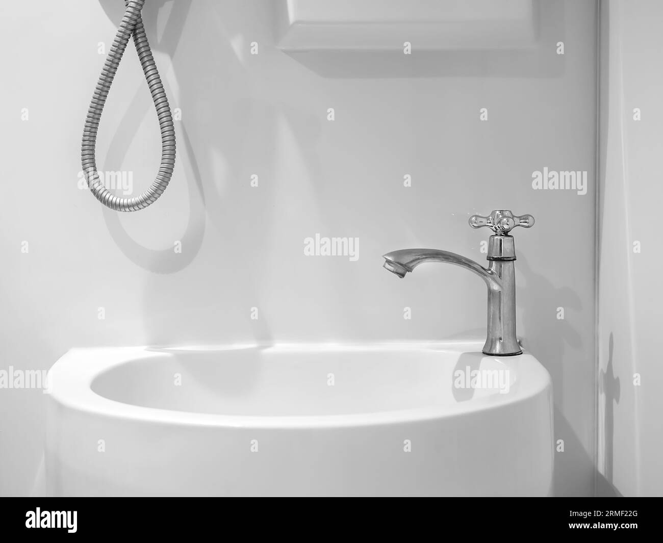 Interno del bagno bianco e pulito con semplice rubinetto cromato su lavandino vuoto su sfondo bianco. Design moderno con bagno prefabbricato, toilette e polveri Foto Stock