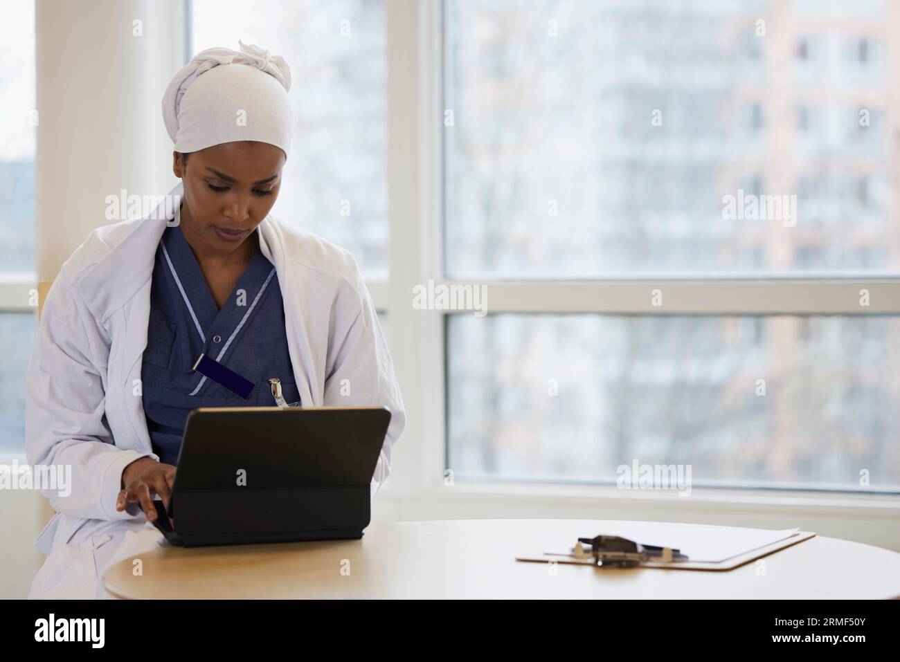 Giovane medico donna che usa una compressa al lavoro Foto Stock