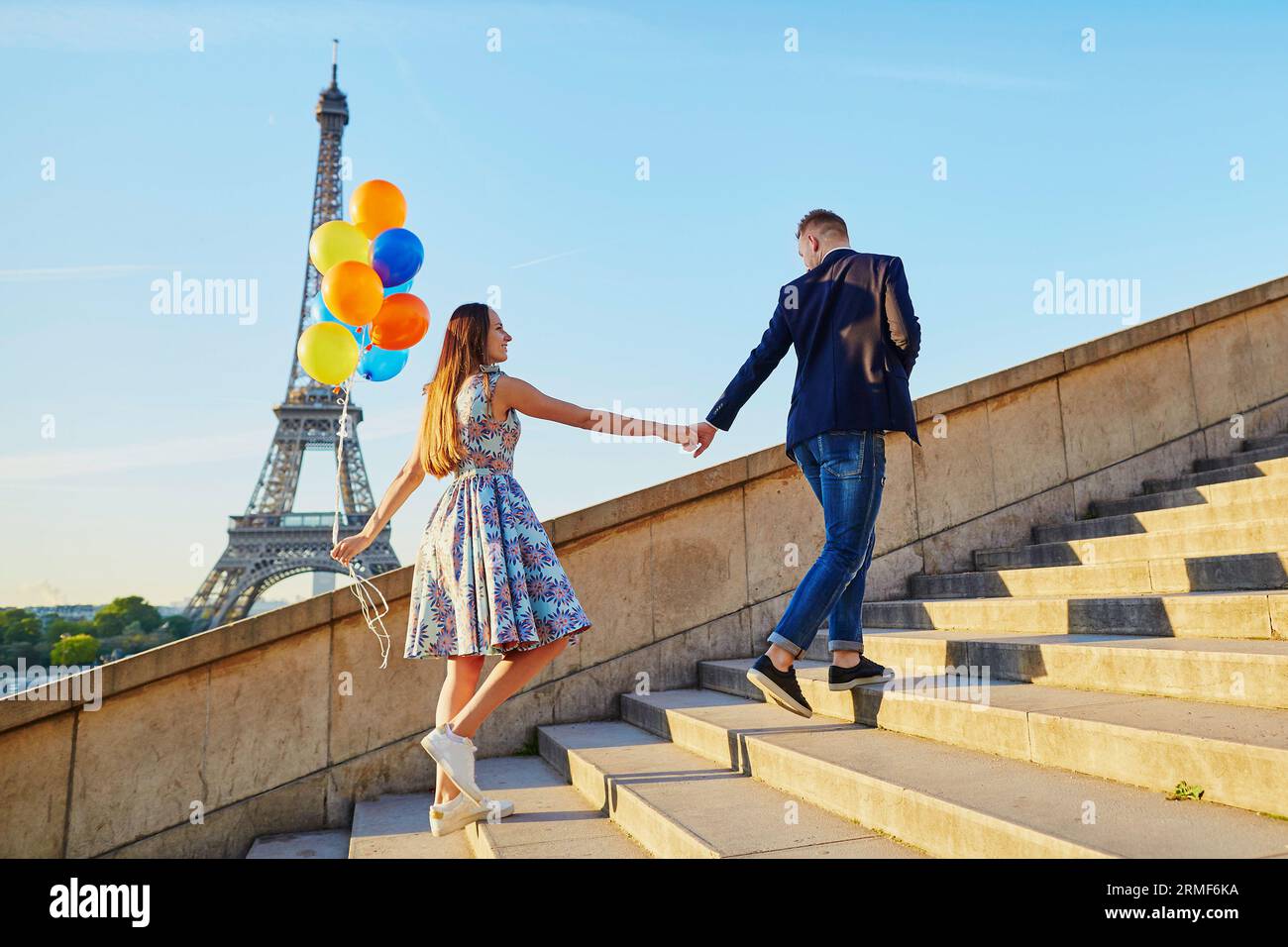 Coppia romantica con palloncini colorati vicino alla Torre Eiffel a Parigi, Francia, salendo le scale Foto Stock