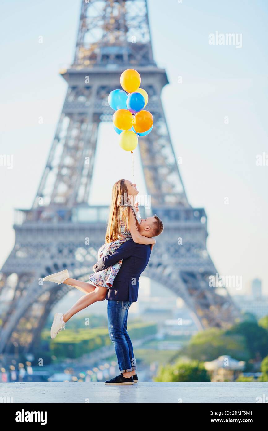Coppia amorevole con un sacco di palloncini colorati che si divertono vicino alla Torre Eiffel a Parigi, in Francia Foto Stock