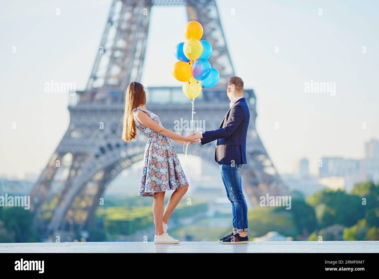 Coppia amorevole con un mucchio di palloncini colorati che guardano la Torre Eiffel a Parigi, in Francia Foto Stock