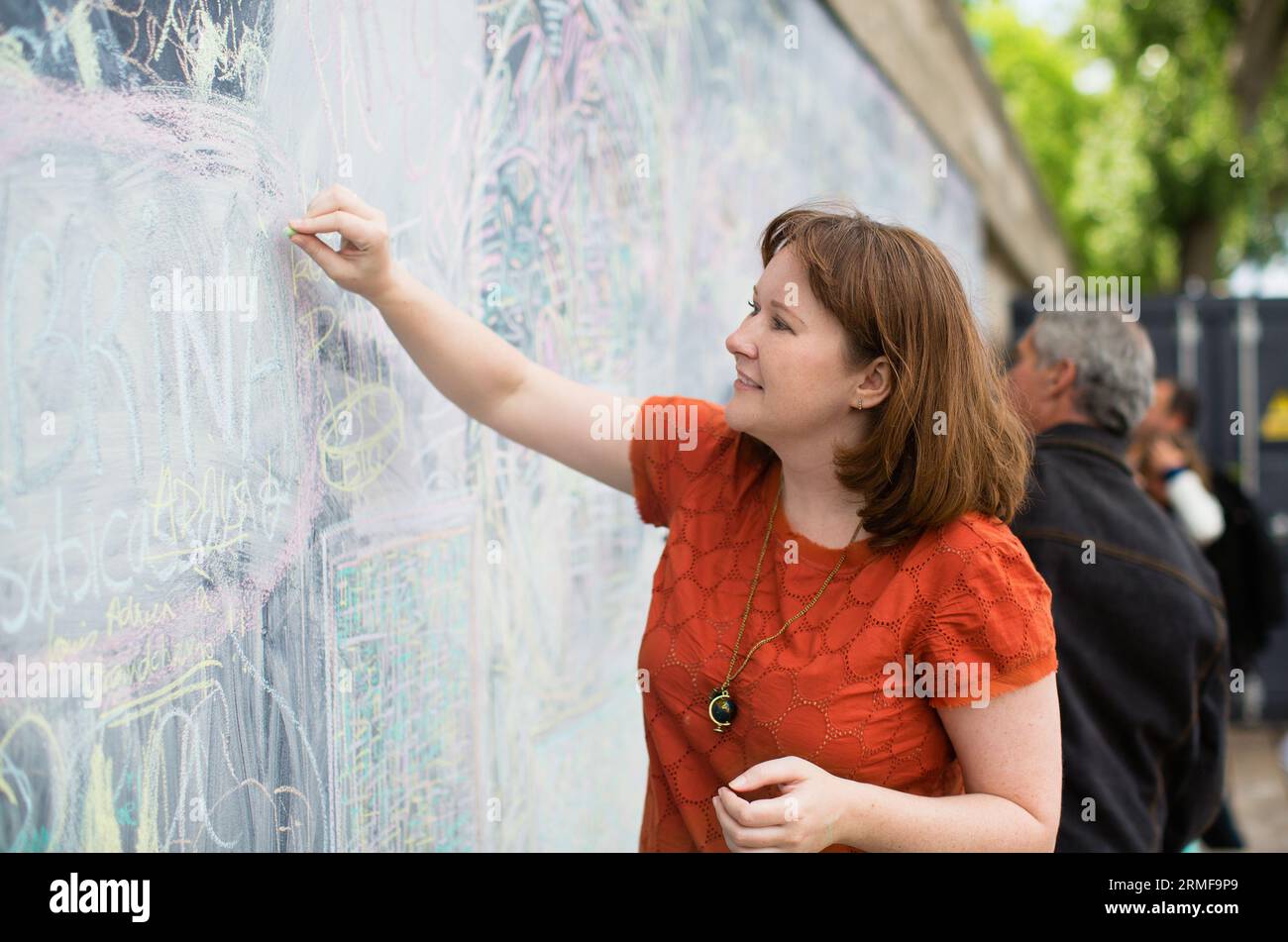 Ragazza che disegna con gesso nell'area del passaggio pedonale sul terrapieno della Senna Foto Stock