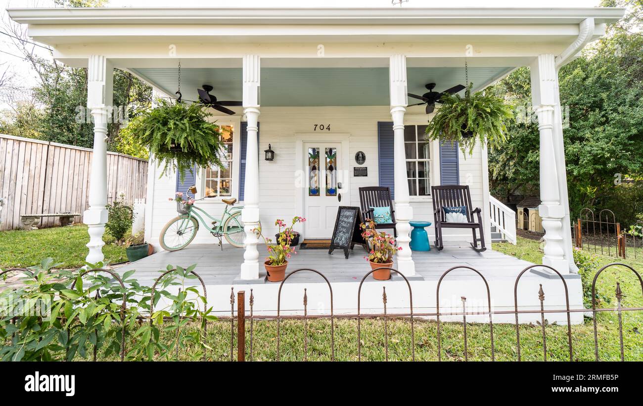 Un caratteristico cottage con un invitante portico con mobili da esterno e piante in vaso, perfetto per un'intima giornata estiva Foto Stock