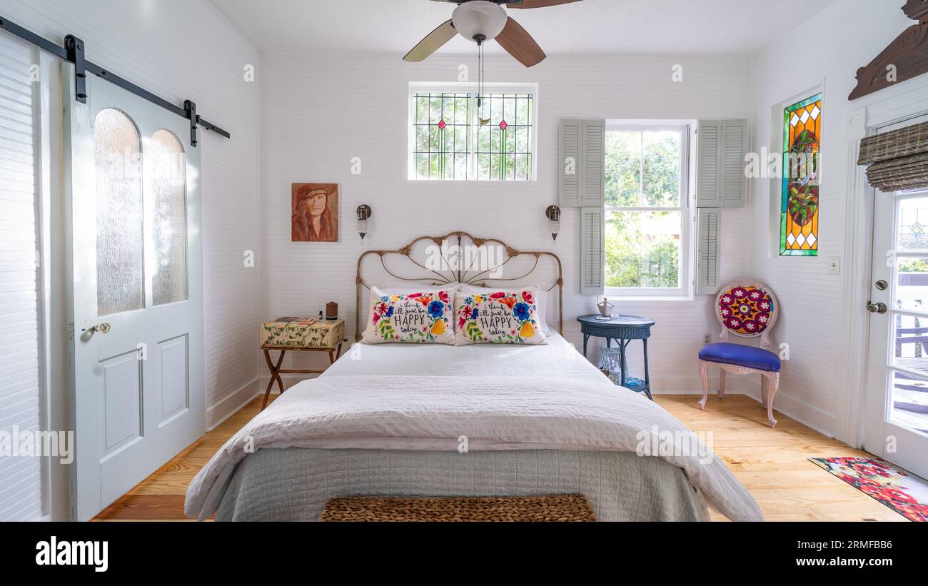 Una camera da letto accogliente e invitante con un letto bianco decorato con una varietà di cuscini vivaci Foto Stock
