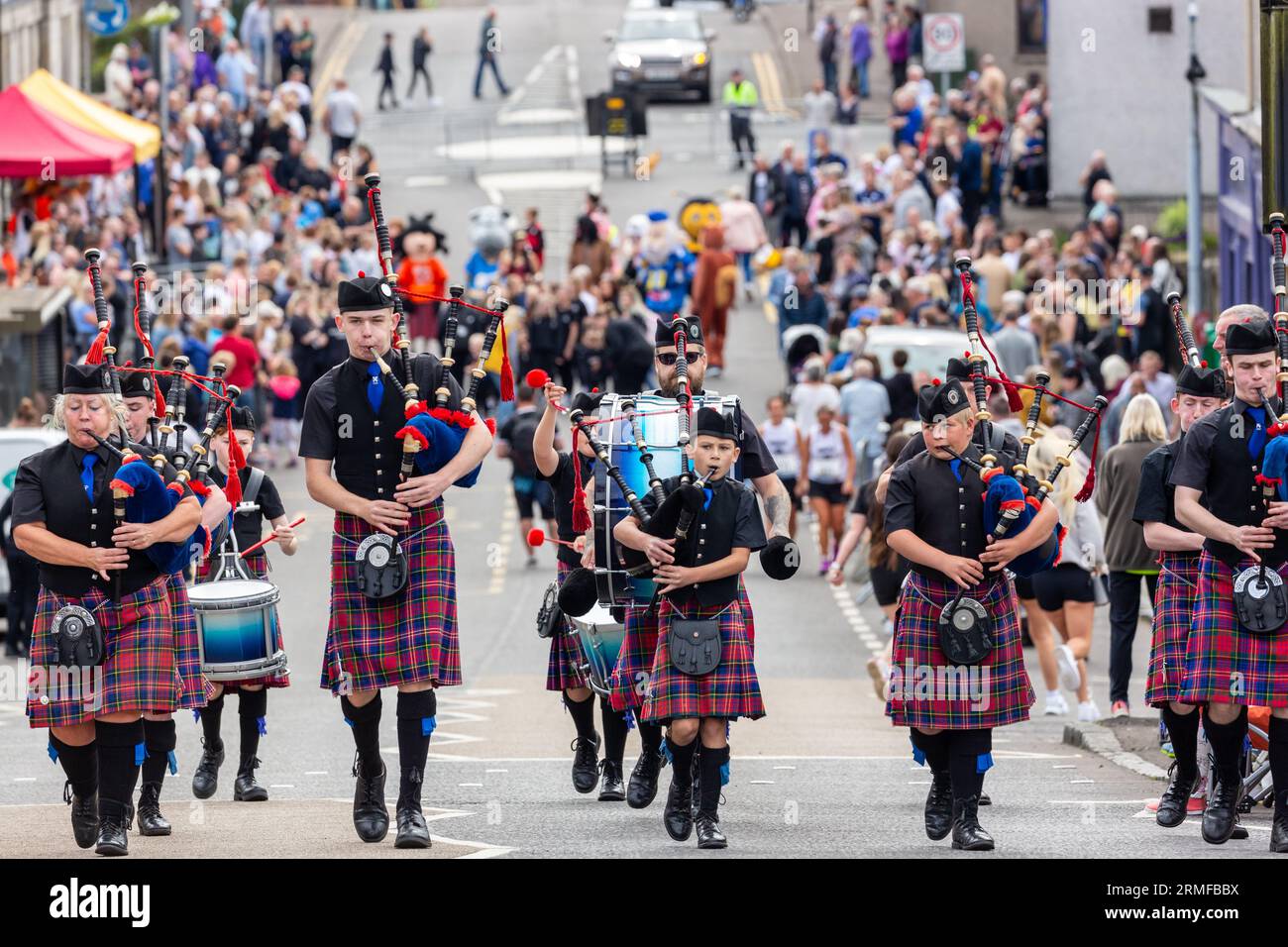 Una Scottish Pipe Band che marciava per strada prima degli Scottish Coal Carating Championships, Kelty, Fife Foto Stock