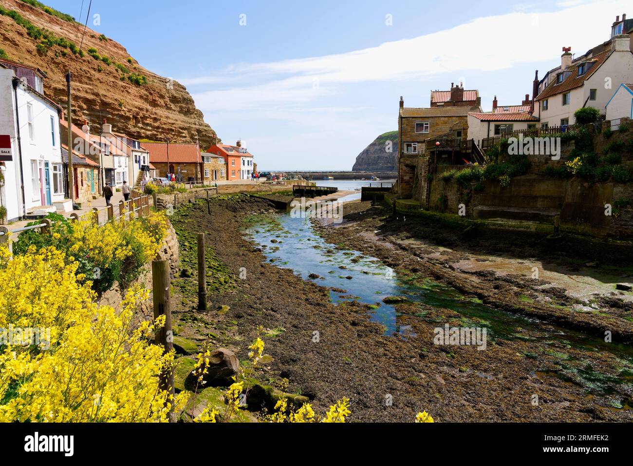 Staithes, Inghilterra - 24 maggio 2023: Un piccolo numero di abitanti del luogo e visitatori di Staithes e Cowbar approfittano del sole primaverile. Foto Stock