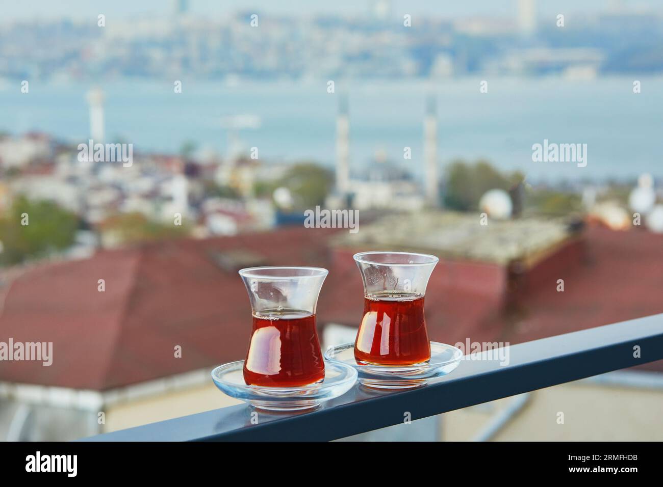 Due bicchieri turchi a forma di tulipano riempito di tè nero caldo con vista sui tetti del distretto di Uskudar sul lato asiatico di Istanbul, Turchia Foto Stock