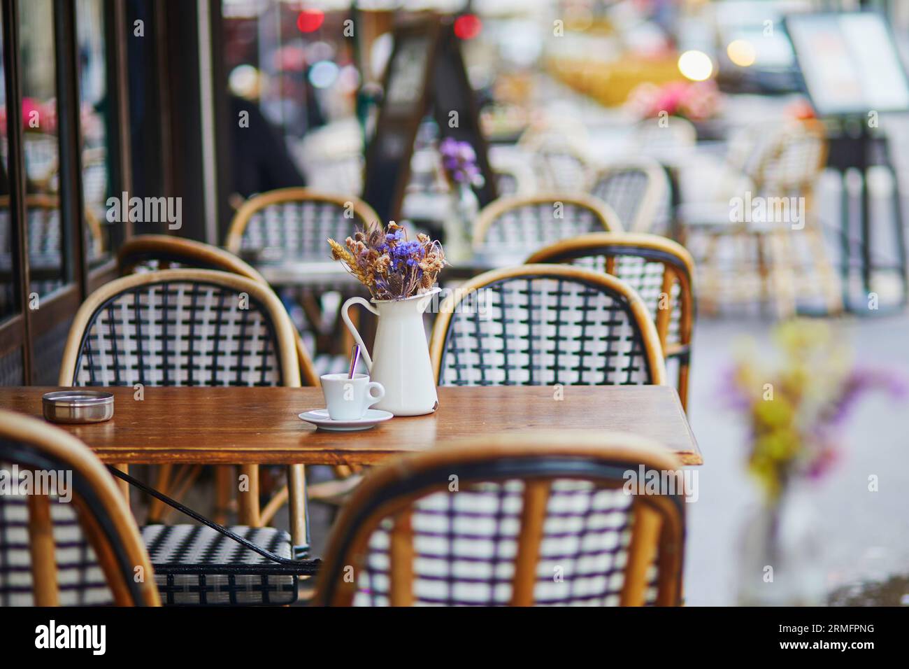 Tavolo del tradizionale caffè all'aperto parigino. Tazza di caffè e caraffa con fiori secchi nel ristorante vuoto di Parigi, Francia Foto Stock