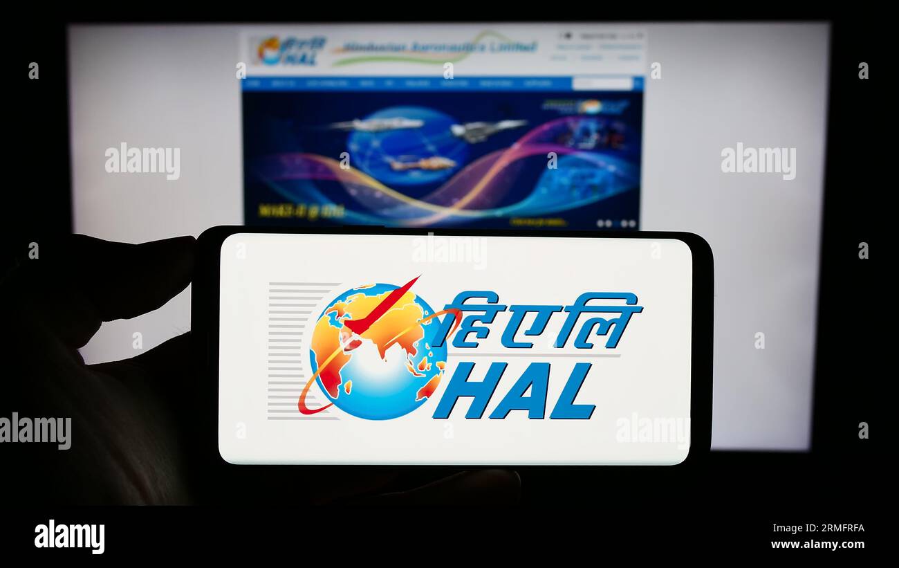 Persona che possiede un telefono cellulare con il logo della società Hindustan Aeronautics Limited (HAL) sullo schermo davanti alla pagina Web. Concentrarsi sul display del telefono. Foto Stock
