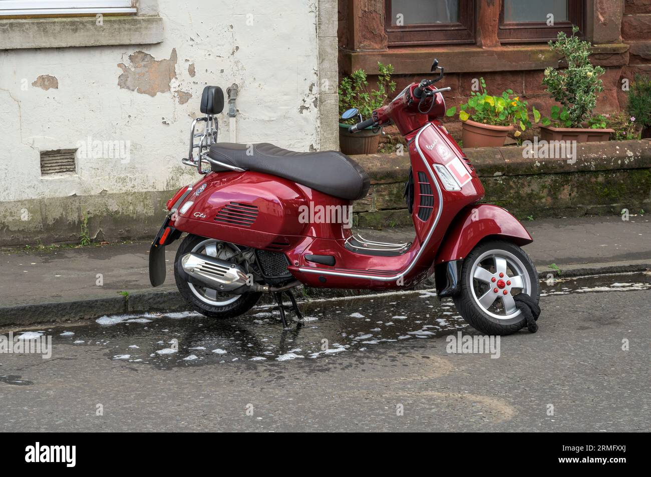 Una Vespa rossa appena lavata parcheggiata al bordo della strada, Scozia, Regno Unito, Europa Foto Stock