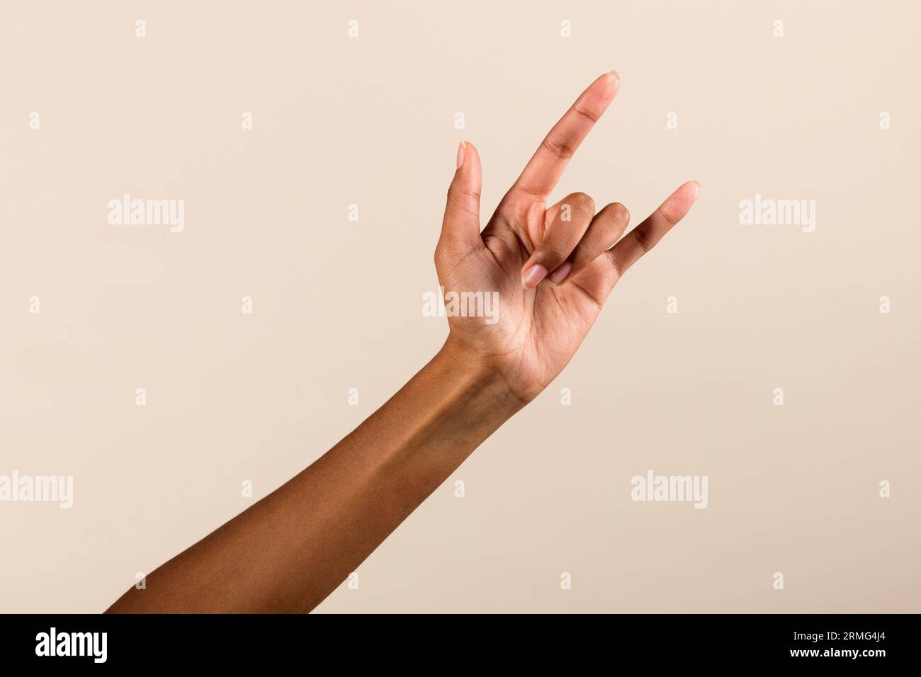 Mano di raccolto femmina afroamericana che mostra il cartello del corno su sfondo grigio in studio Foto Stock