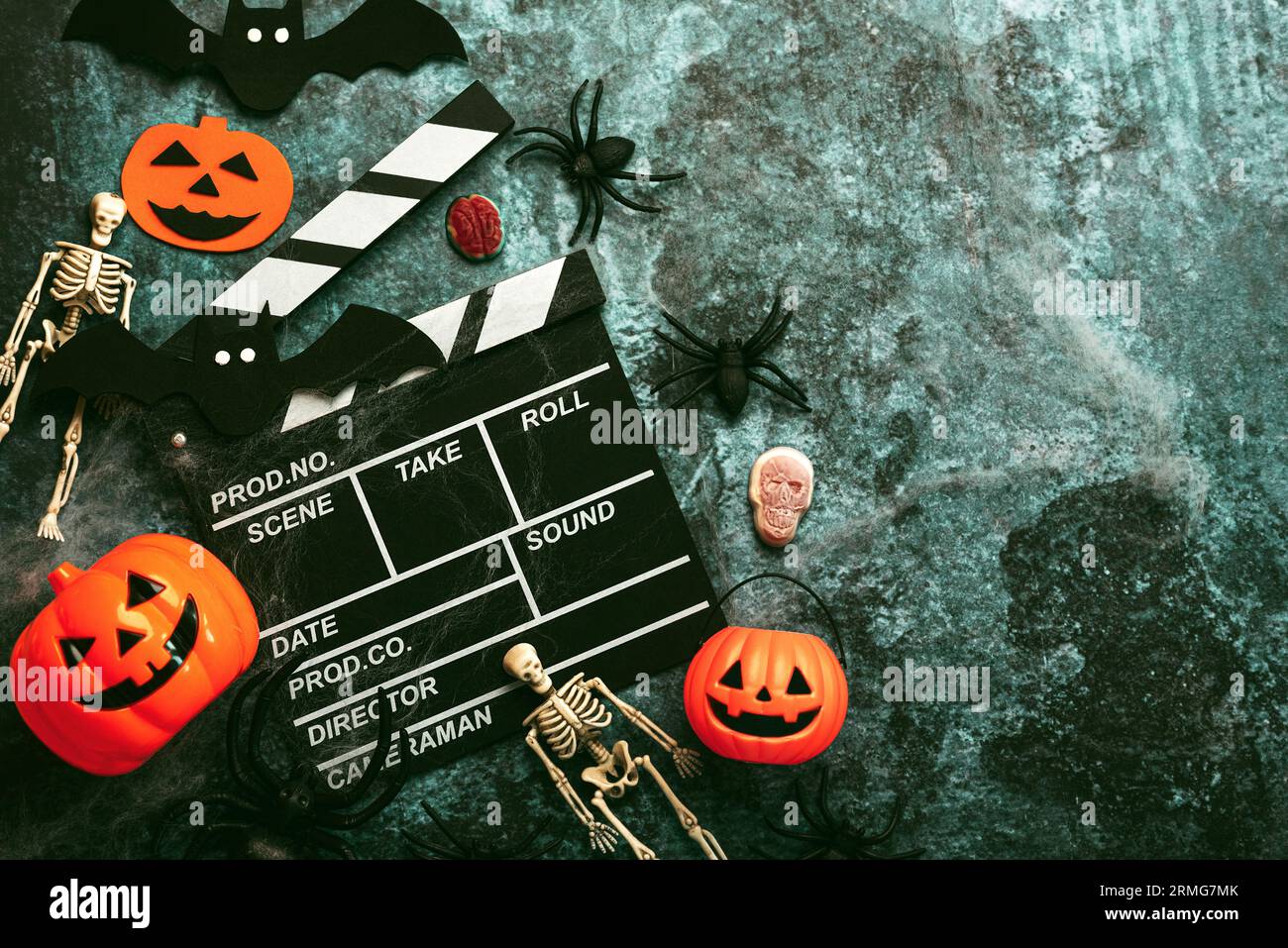 Concetto di film di Halloween. Clapperboard cinematografico con divertente zucca di halloween, scheletri e ragni su sfondo grunge. Sfondo del concetto di Halloween Foto Stock