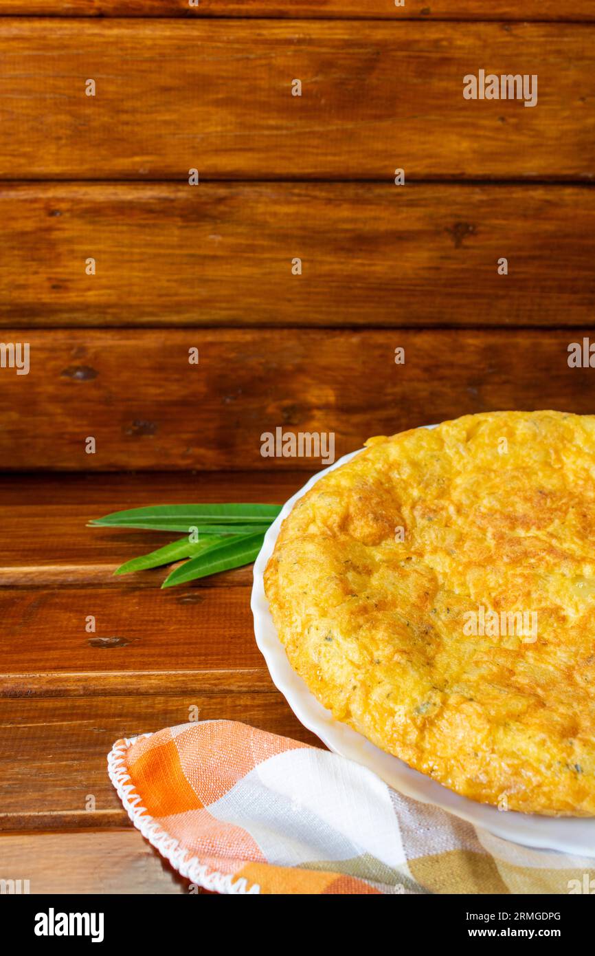 primo piano verticale della frittata spagnola con tovagliolo a scacchi tonalità arancio su sfondo di legno scuro Foto Stock