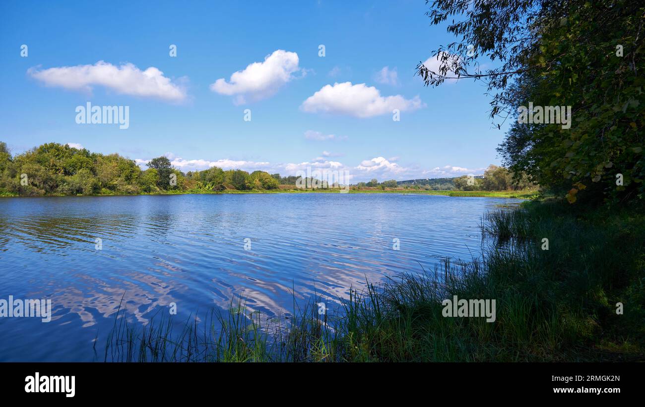 Splendido paesaggio estivo con fiume, alberi e cielo blu con nuvole Foto Stock