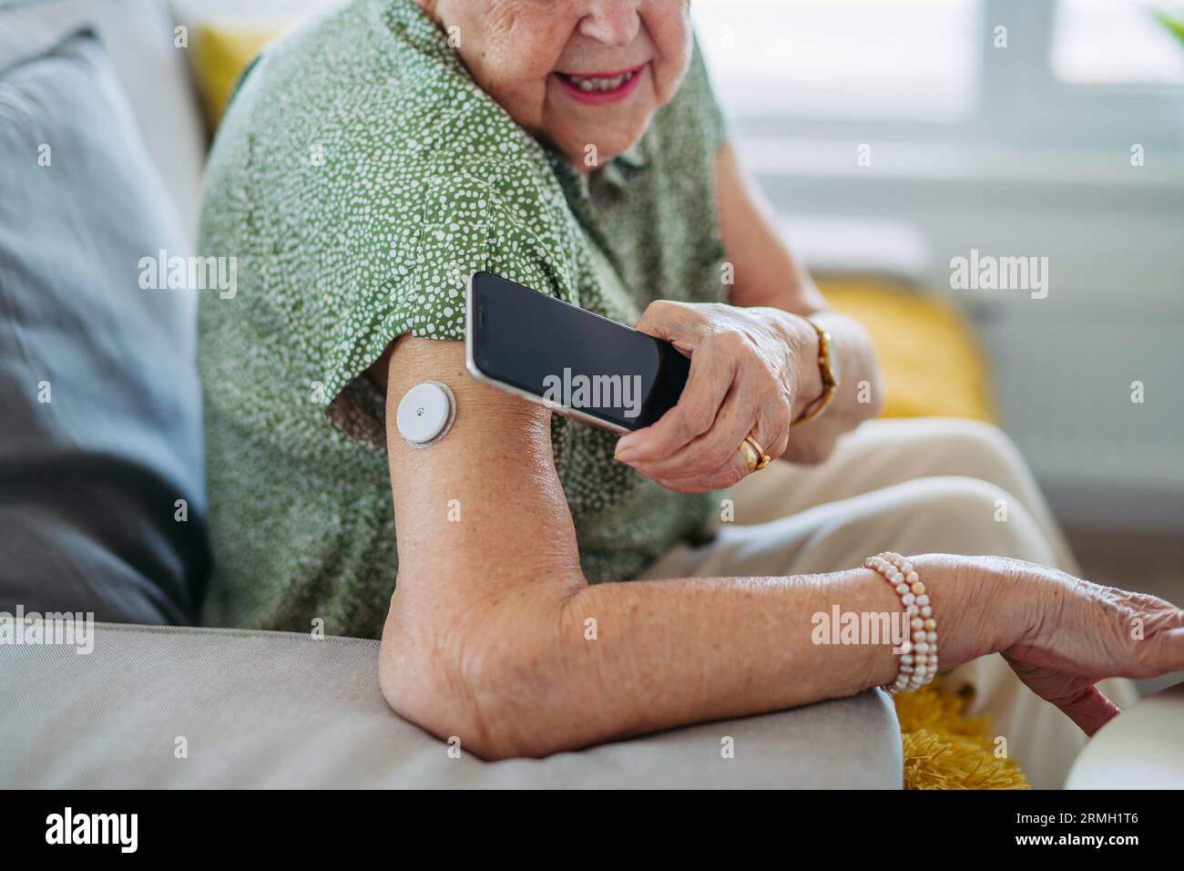 Primo piano del paziente diabetico anziano che controlla il livello di glucosio nel sangue a casa utilizzando il monitor continuo della glicemia. Foto Stock