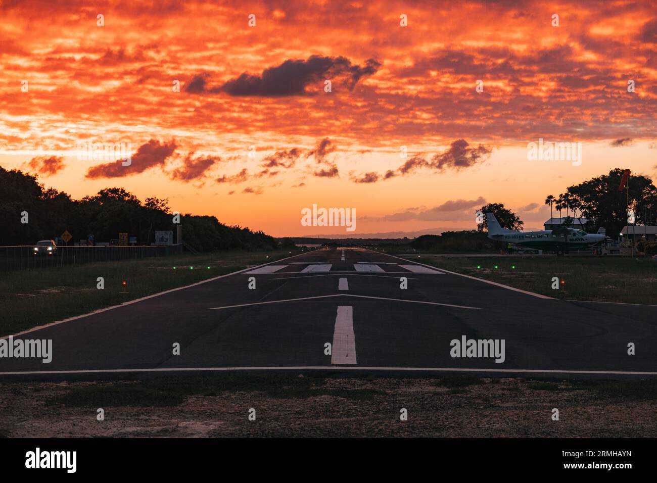 I colori oro e arancio del tramonto colpiscono la pista dell'aeroporto di Placencia, nel Belize sud-orientale Foto Stock