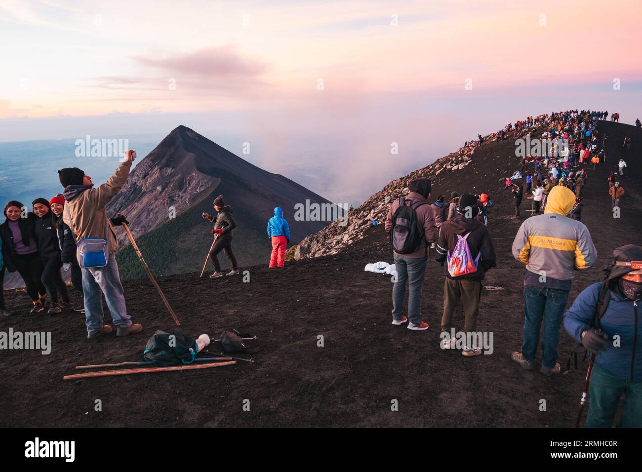 Dozzine di turisti affollano la cima del vulcano Acatenango dormiente in Guatemala per osservare l'adiacente e attivo vulcano Fuego eruttare, all'alba Foto Stock