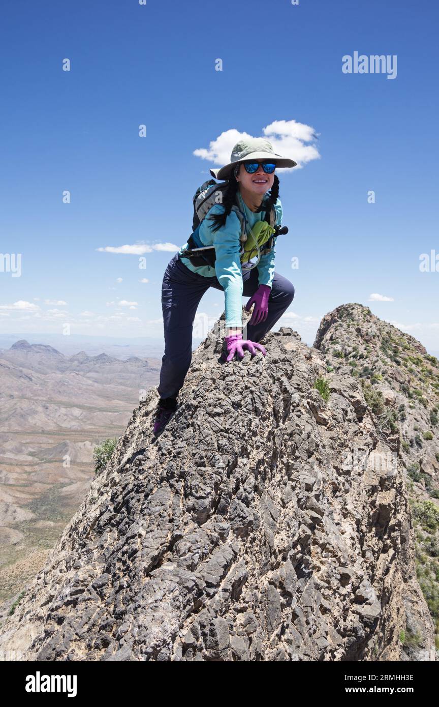 Una donna asiatica che si arrampica lungo la catena montuosa del Moapa Peak Foto Stock