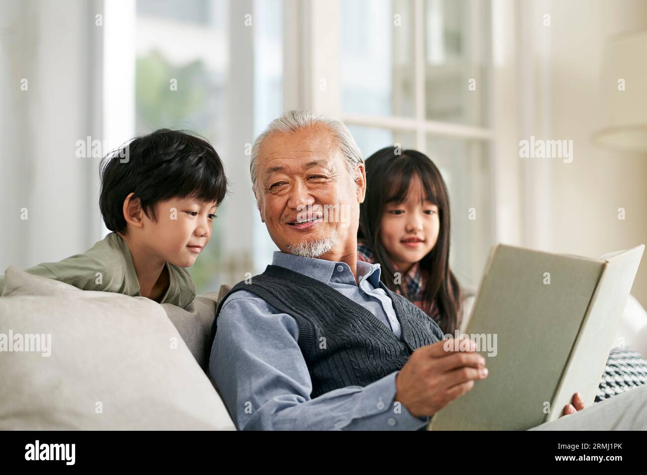 nonno asiatico che si diverte a raccontare la storia a carini nipoti e nipoti Foto Stock