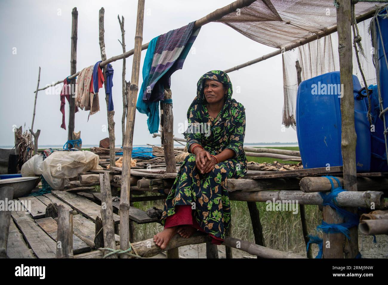 26 agosto 2023, Khulna, Bangladesh: Mohiful Begum (35) posa una foto davanti alla sua casa danneggiata in un'area costiera a Kalabogi. Non molto tempo fa Kalabogi, un villaggio costiero del Bangladesh, era pieno di terra coltivabile fino a quando l'innalzamento del livello del mare non cominciò a ingoiare l'area fino alla baia del Bengala. Frequenti cicloni e inondazioni hanno colpito il villaggio dalla fine degli anni '1990 Nel 2009, un grande ciclone chiamato Aila distrusse i 1.400 chilometri di argini, 8.800 chilometri di strade e circa 50.000 ettari di terreno agricolo. Diverse centinaia di persone sono state uccise nel di Foto Stock