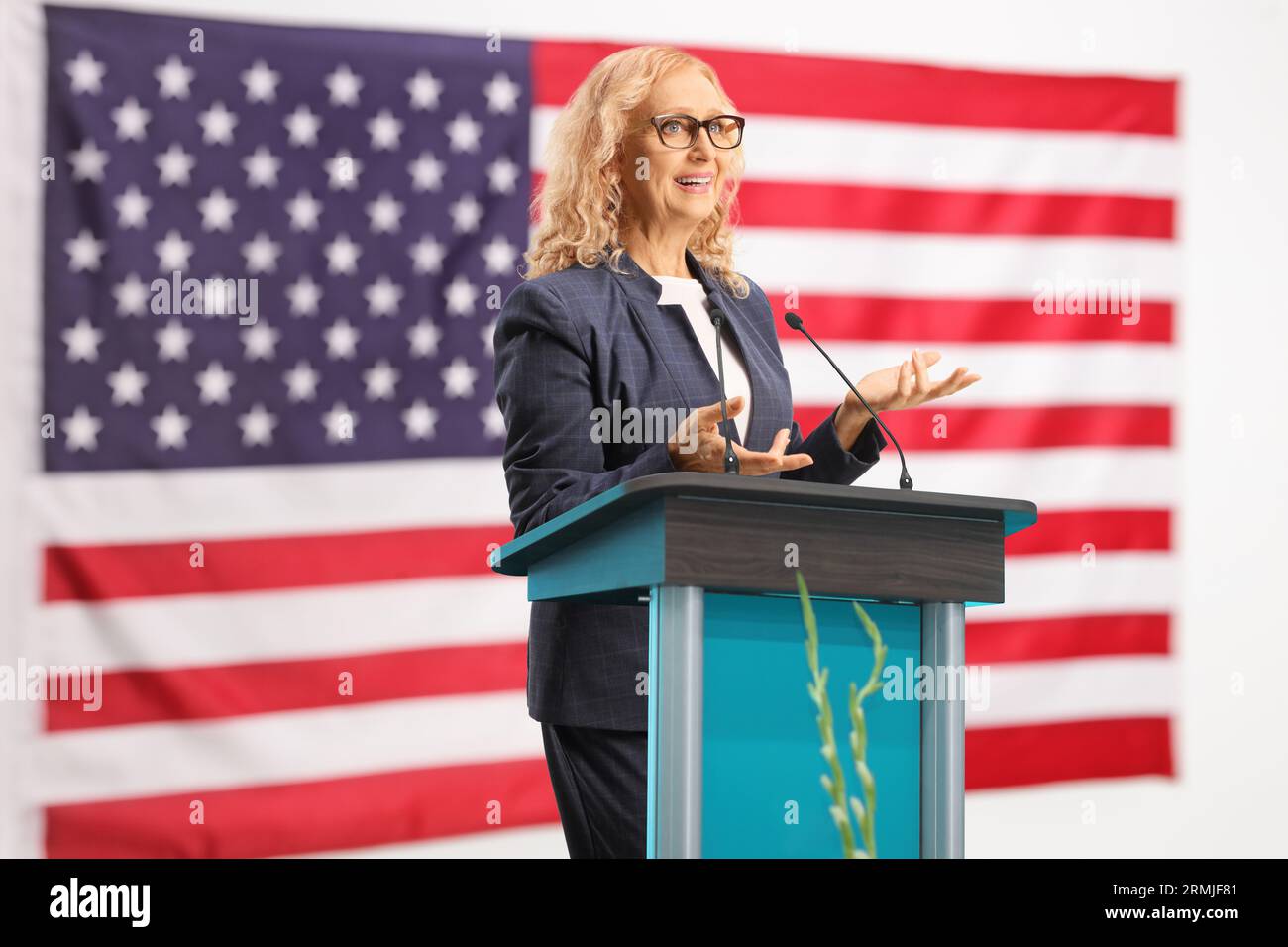 Donna politica che tiene un discorso su una posizione con la bandiera degli Stati Uniti dietro Foto Stock