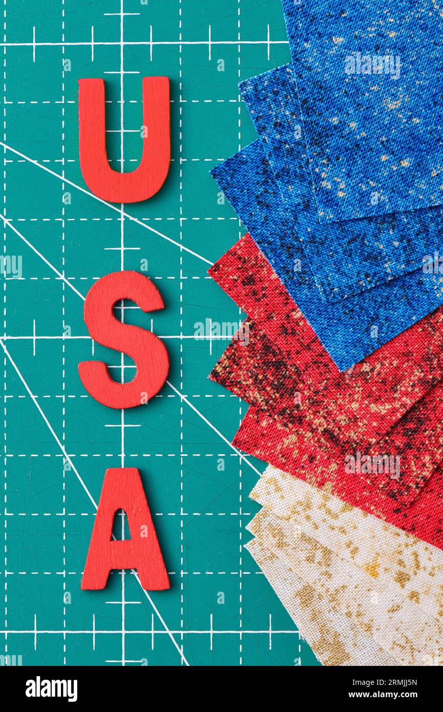 Lettere in legno che riportano l'abbreviazione USA e pezzi quadrati di tessuto nei colori della bandiera USA su un tappeto verde Foto Stock