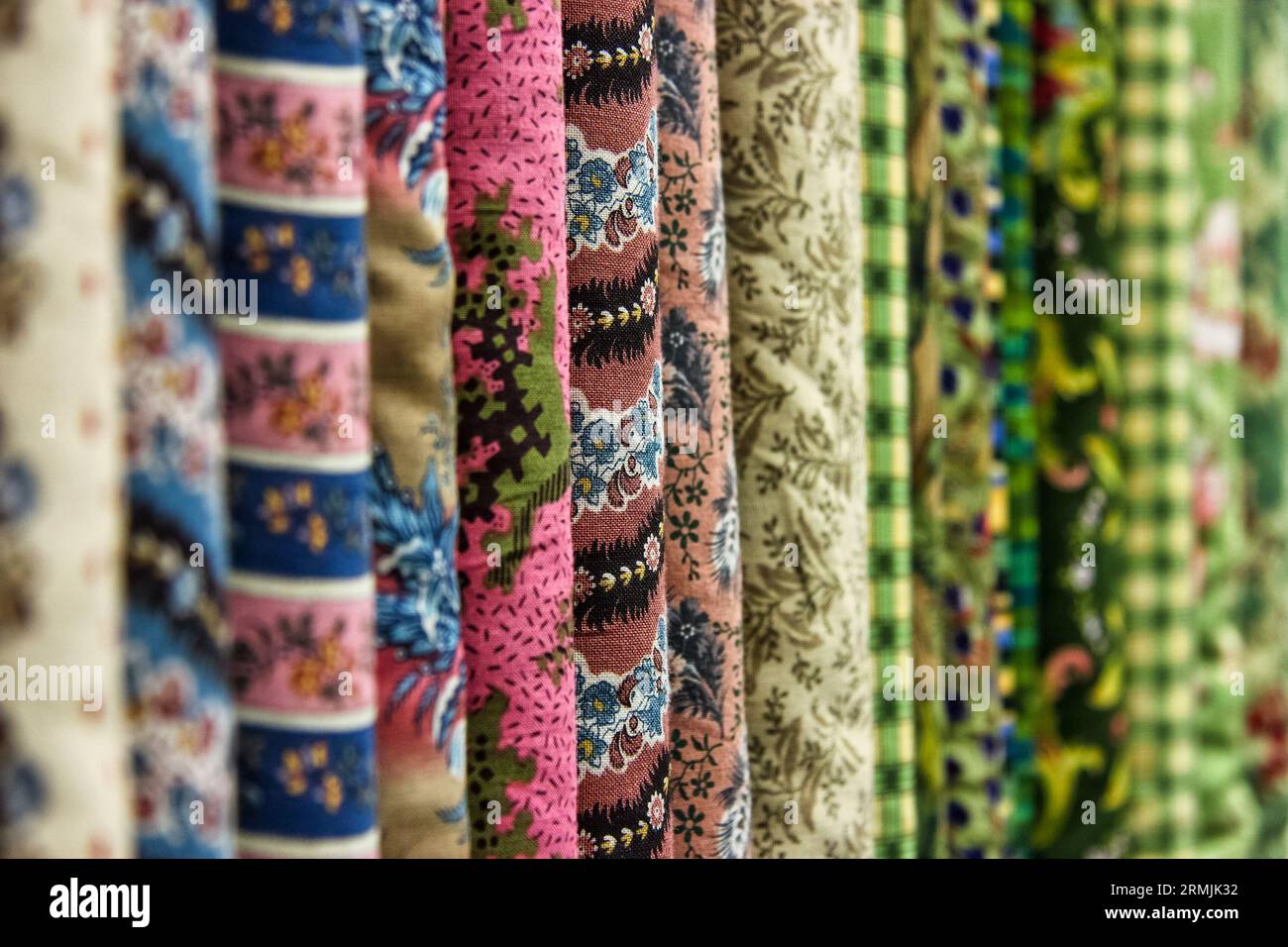Una fila di tessuti con motivi e colori diversi. La foto viene scattata da una prospettiva diretta e cattura i dettagli del tessuto. Foto Stock