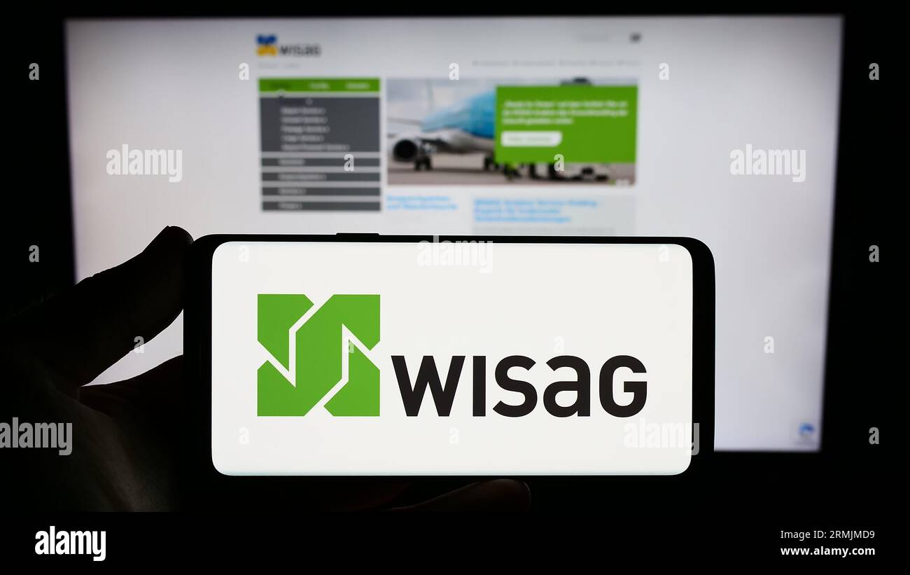Persona che possiede uno smartphone con il logo della società tedesca WISAG Dienstleistungsholding se sullo schermo davanti al sito Web. Concentrarsi sul display del telefono. Foto Stock
