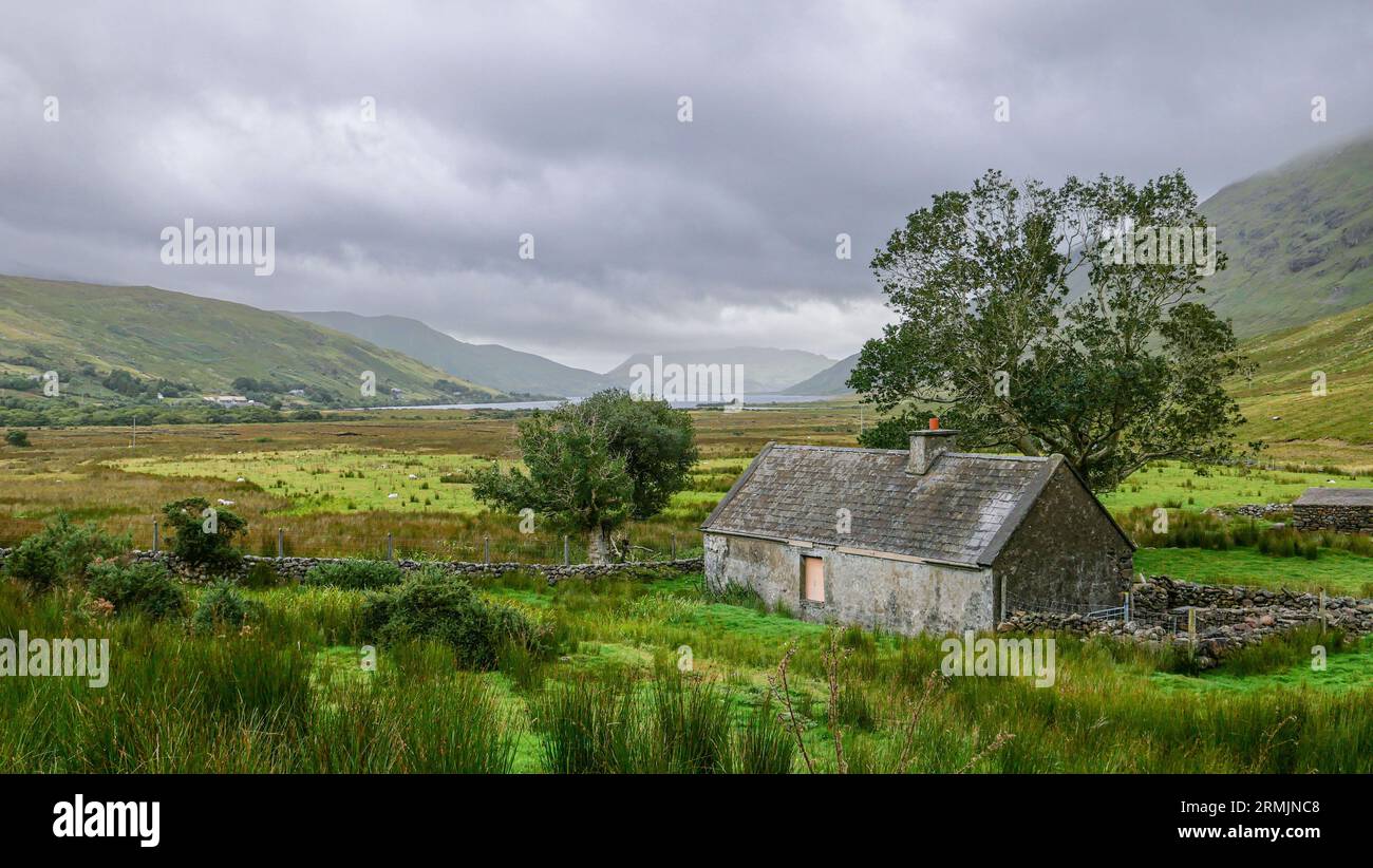 Irlanda, Connemara, Contea di Mayo: Paesaggio tipico sotto un cielo tempestoso. Vecchio edificio, fattoria isolata Foto Stock