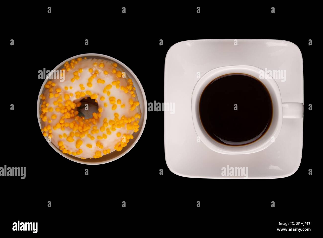 Ciambella con spruzzi colorati e tazza di caffè isolata su sfondo nero scuro. Dolcezza in piedi da soli su uno sfondo solido. Foto Stock