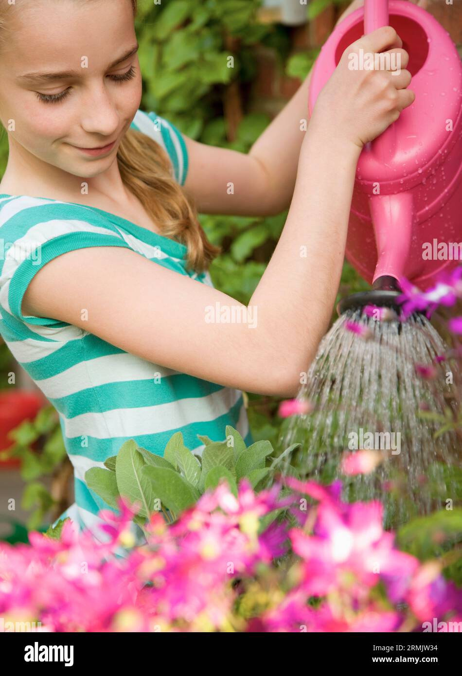 Ritratto di una giovane ragazza di innaffiamento con fiori rosa annaffiatoio Foto Stock
