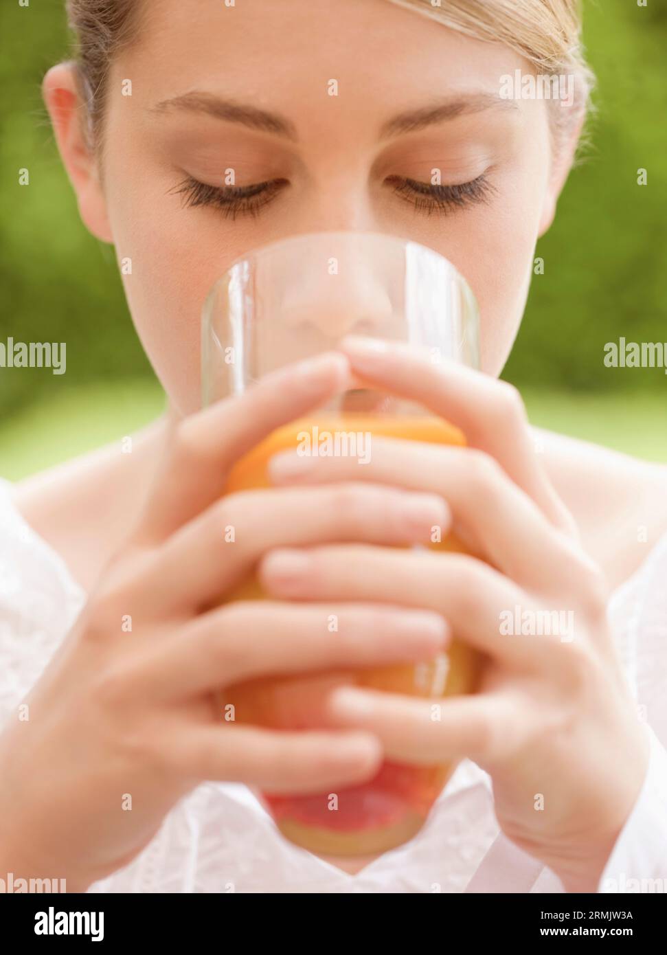 In prossimità di una giovane donna di bere e tenendo un bicchiere di succo di arancia Foto Stock