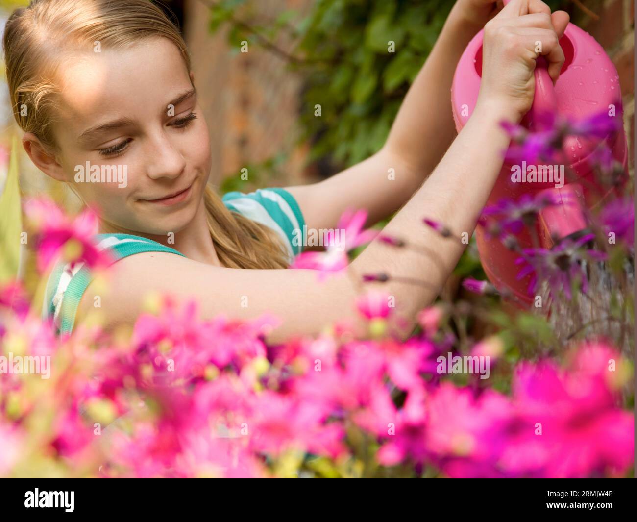Ritratto di una giovane ragazza di innaffiamento con fiori rosa annaffiatoio Foto Stock