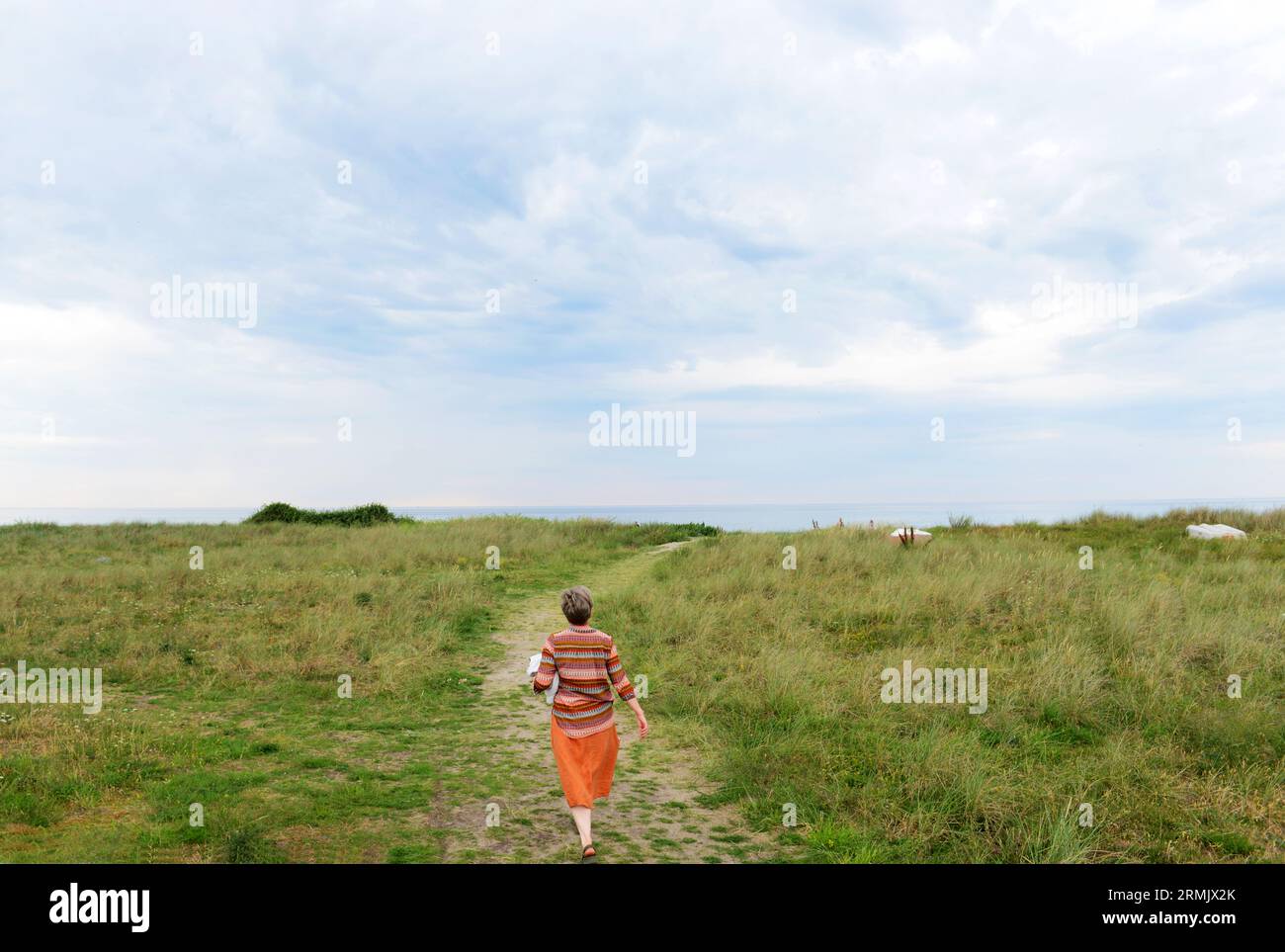 Una donna danese che cammina verso la spiaggia di Frølunde Fed, in Zelanda, Danimarca. Foto Stock