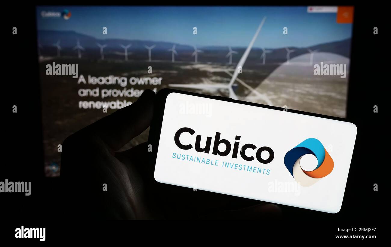 Persona che possiede uno smartphone con il logo della società cubico Sustainable Investments Limited sullo schermo di fronte al sito Web. Concentrarsi sul display del telefono. Foto Stock