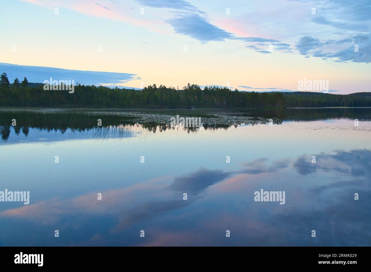 Calmo lago in Svezia al tramonto all'ora blu. Nuvole riflesse nell'acqua. Nuotare e divertirsi in vacanza con attività ricreative in Scandinavia Foto Stock