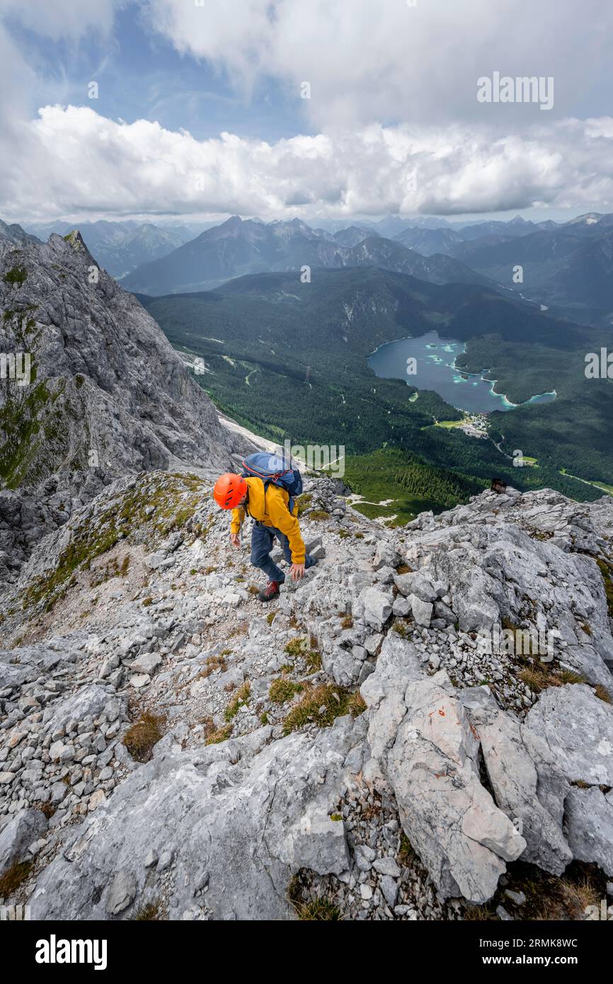 Arrampicata su Waxenstein su un sentiero roccioso esposto, vista del lago Eibsee, paesaggio roccioso tortuoso, montagne Wetterstein, Garmisch-Partenkirchen Foto Stock