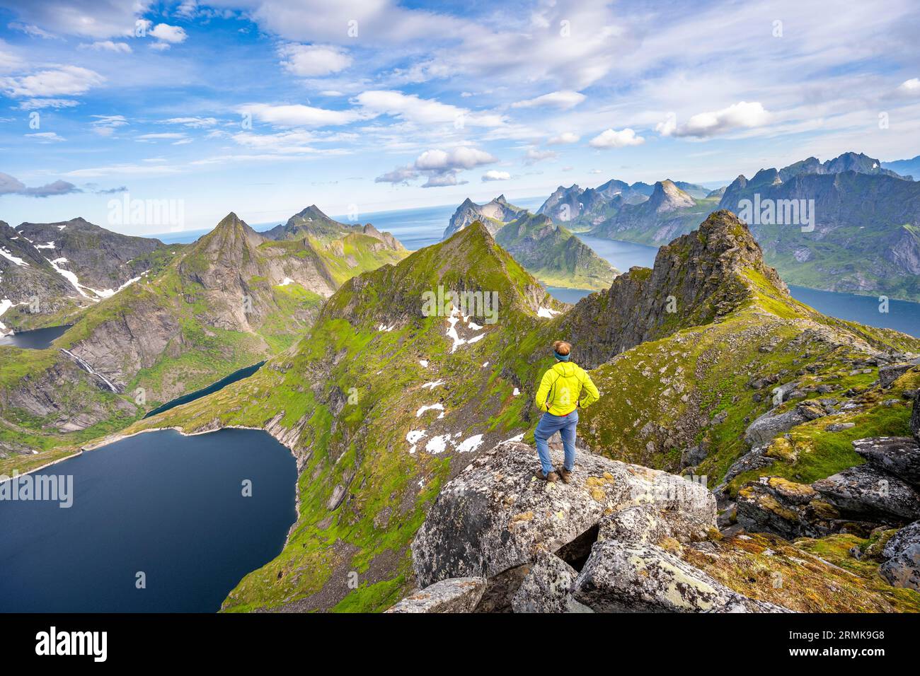 Alpinisti in cima al Munken, paesaggio montano con ripide cime rocciose, il lago Tennesvatnet fiordi e il mare, vista dalla cima del Foto Stock