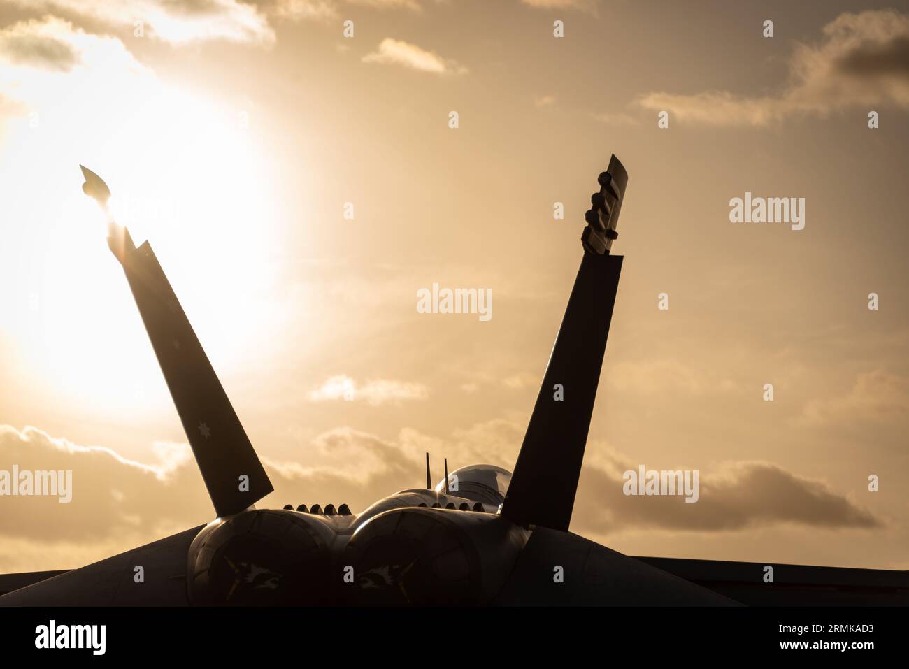 Silhouette di un moderno caccia militare contro un cielo dorato Foto Stock