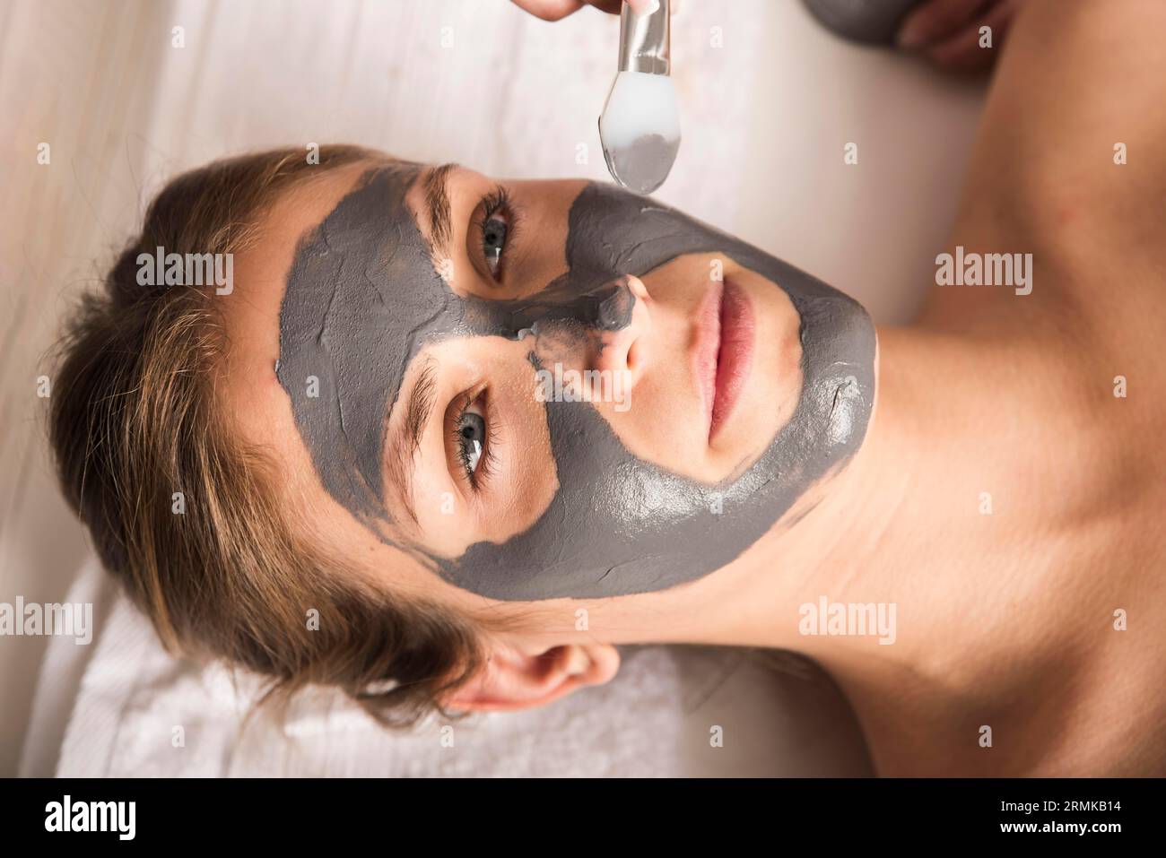 Bella giovane donna che applica maschera viso il suo viso Foto Stock