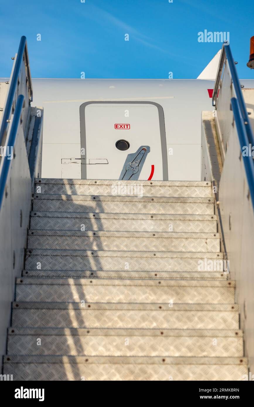 Guardando una serie di aerei salire le scale verso una fusoliera grigia di un aereo contro un cielo blu, verticale Foto Stock