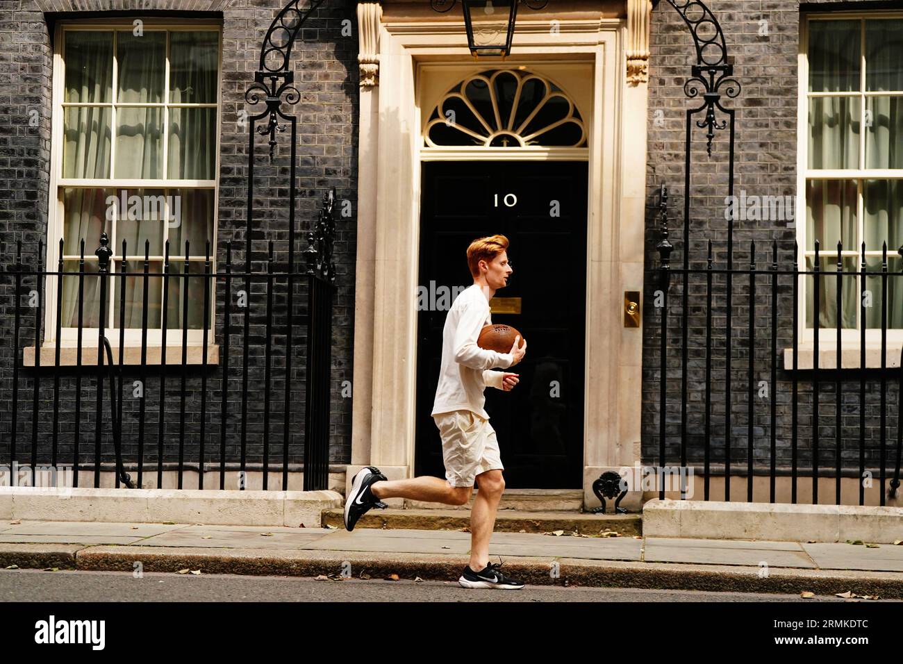 Jake Barraclough corre con una palla di rugby fuori dal 10 di Downing Street, Londra, in occasione del 200° anniversario della creazione del gioco di rugby correndo i 450 km dalla Rugby School a Parigi, prima della Coppa del mondo di rugby in Francia. Data foto: Martedì 29 agosto 2023. Foto Stock