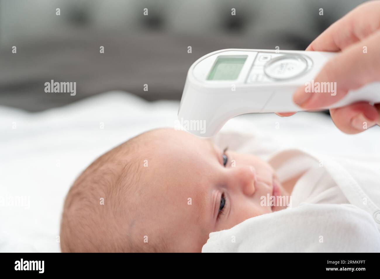 Il termometro digitale mette in risalto l'istinto protettivo della mamma. Concetto di moderni metodi di cura materna Foto Stock