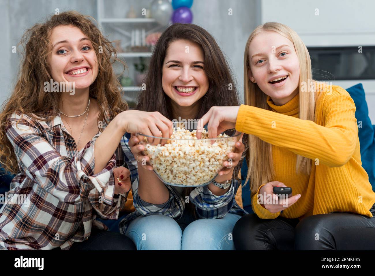 Amici che guardano un film mentre mangiano popcorn Foto Stock