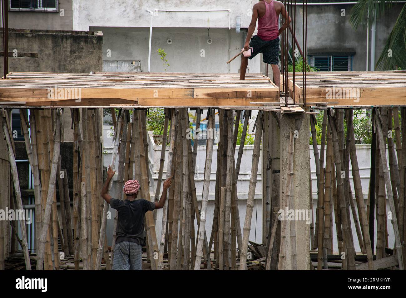 I massoni stanno lavorando con bamboo e pannelli di legno in un alto edificio in costruzione Foto Stock