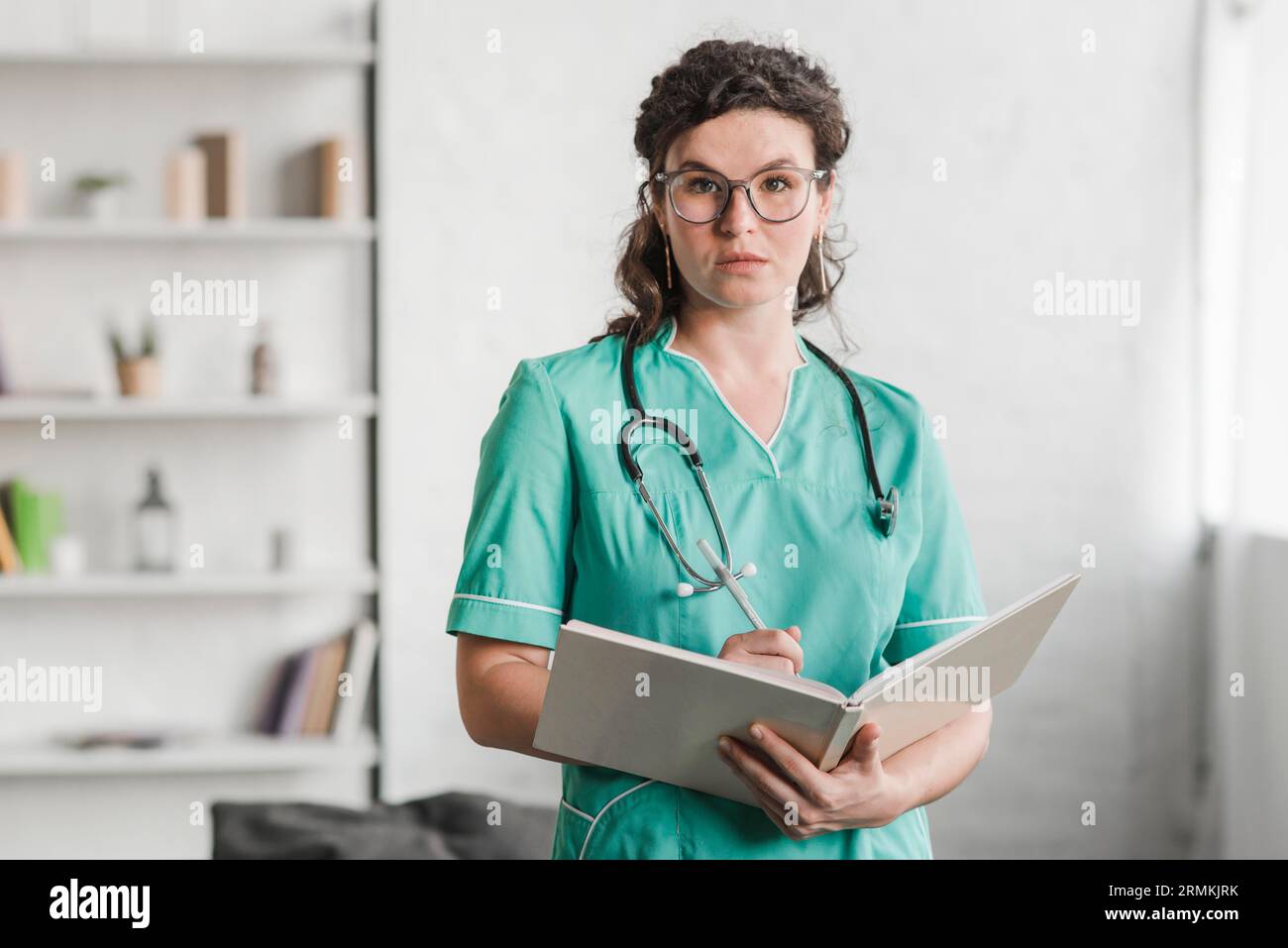 Ritratto infermiera donna che tiene la penna del libro Foto Stock