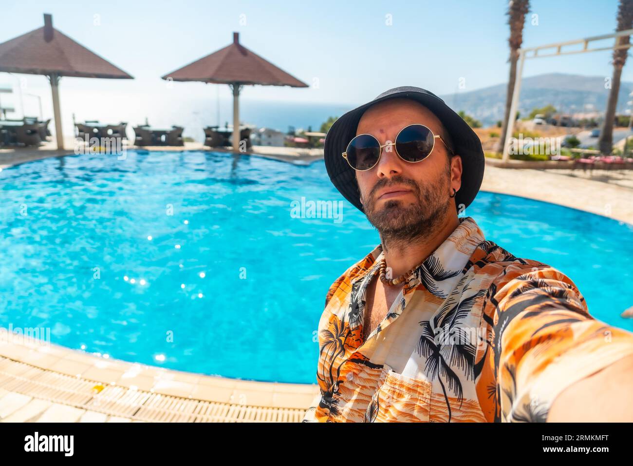 Turista nella piscina dell'hotel in estate che si prende un selfie godendosi la vacanza Foto Stock